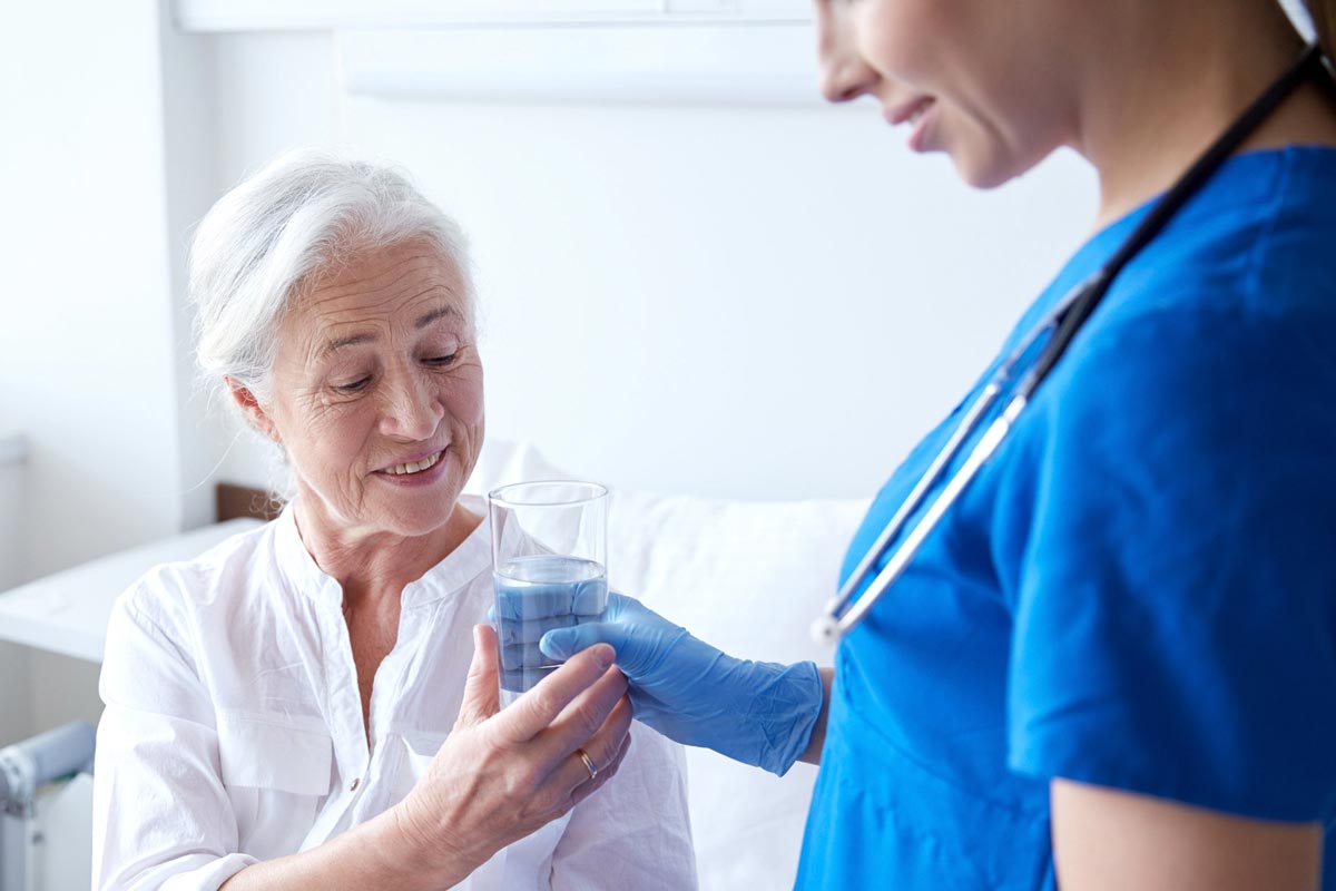 Krankenhaus Patientin bekommt ein Glas Wasser von einer Pflegerin 