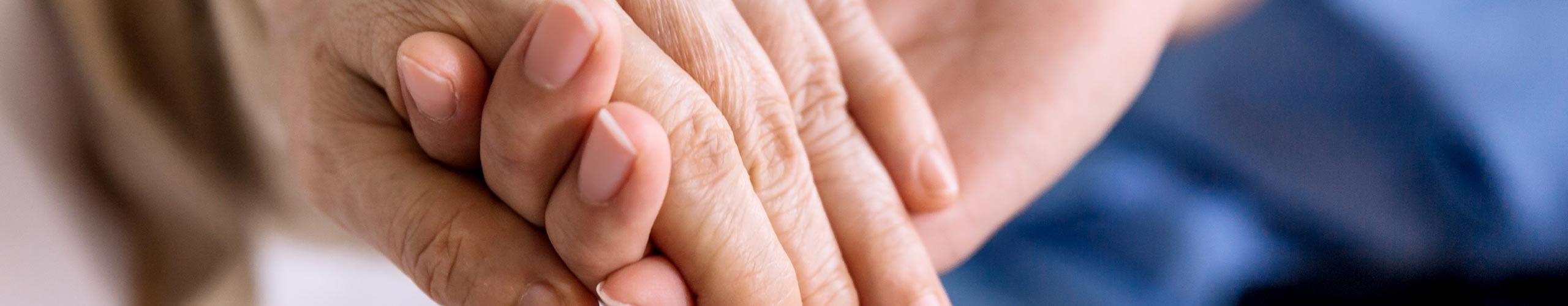 Pflegerin hält Hand einer alten Frau