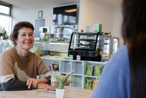 Frau sitzt in der Buchener Cafeteria und trinkt einen Latte Macchiato