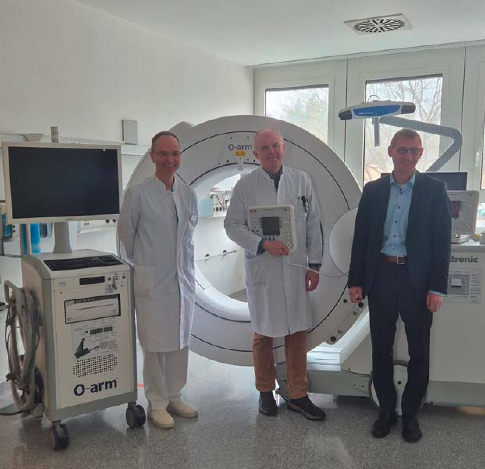 Von links nach rechts: Ärztlicher Direktor Dr. med. Rüdiger Mahler, Sektionsleiter Dr. Attila Tóth und Geschäftsführer Frank Hehn vor dem neuen O-Arm-Gerät. 