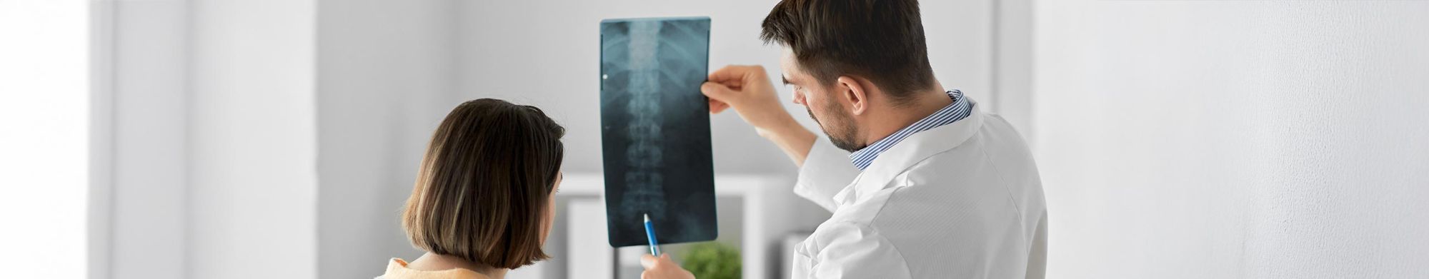 Dekobild Arzt zeigt Patientin Röntgenaufnahme der Wirbelsäule